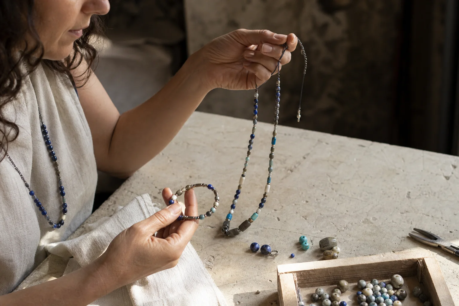 Artesana comparando un collar y una pulsera de piedras naturales sobre su mesa de trabajo