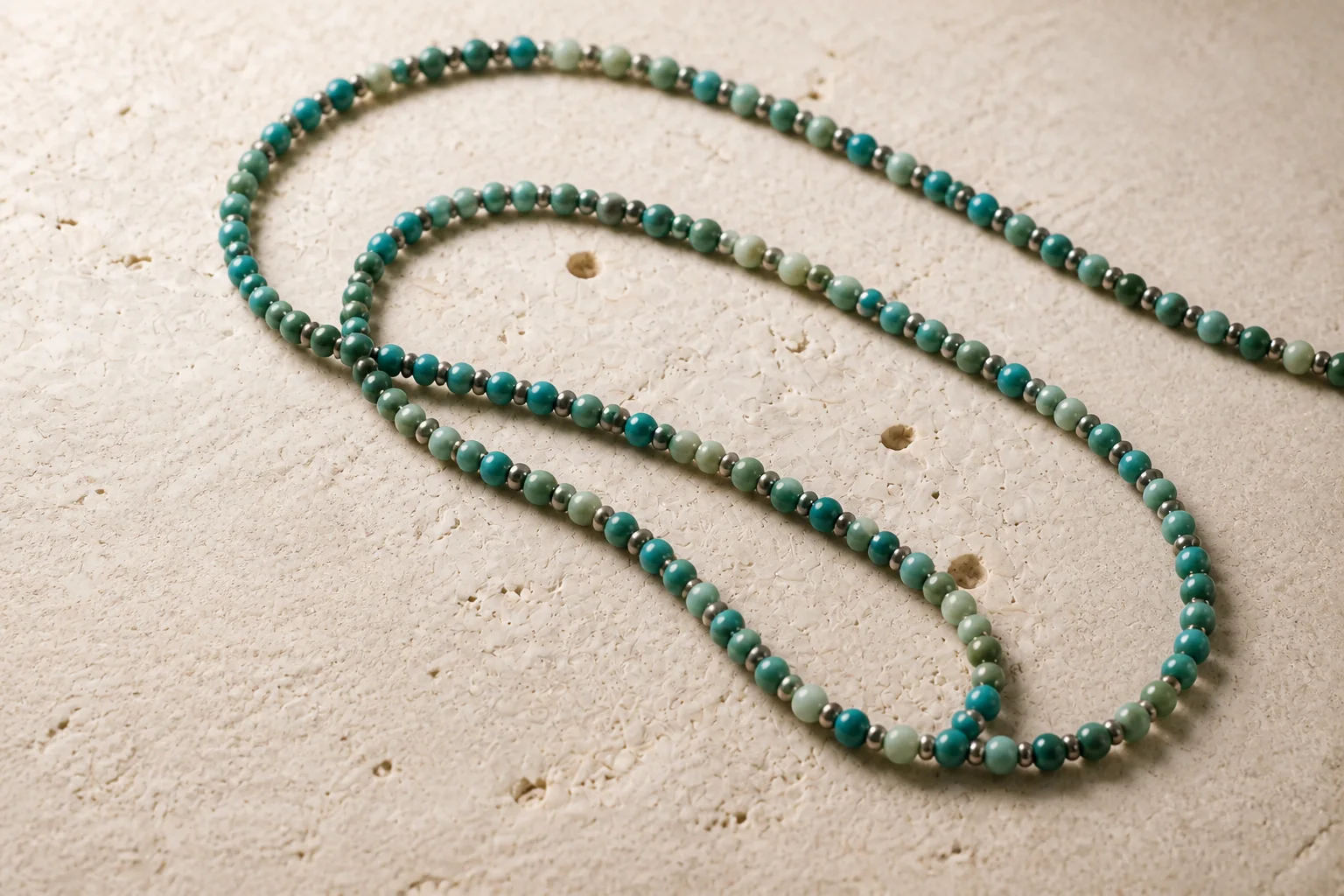 Collar largo de piedras naturales verdes y turquesa sobre piedra caliza